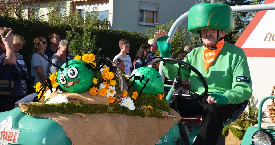 Mottogruppe auf einem grünen Traktor mit Blumen und lustigen Figuren mit Kulleraugen